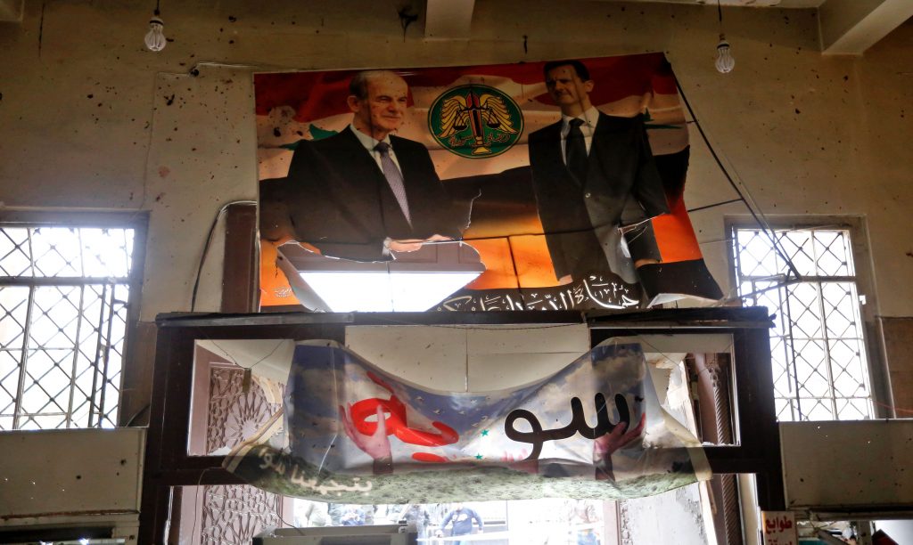 Portraits of Syrian President Bashar al-Assad (R) and his late father former president Hafez al-Assad are seen inside the old palace of justice building in Damascus following a reported suicide bombing on March 15, 2017. Two suicide bombings hit Damascus including the attack at the central courthouse that left at least 32 dead, as Syria's war entered its seventh year with the regime now claiming the upper hand. / AFP PHOTO / Louai Beshara (Photo credit should read LOUAI BESHARA/AFP/Getty Images)