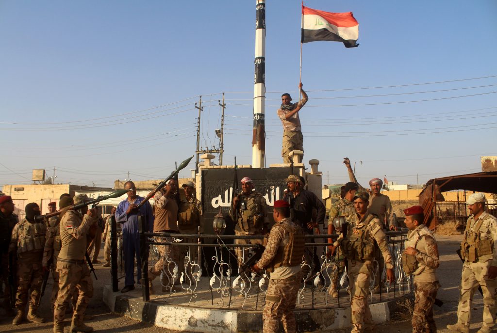 Iraqi government forces raise the Iraqi flag as they celebrate in the al-Bakr neighborhood north of Hit in Iraq's Anbar province after they cleared the area of IS fighters on Oct. 10, 2016. Iraqi security forces have launched a final push to retake Mosul from IS, which seized the country's second city more than two years ago. MOADH AL-DULAIMI/AFP/Getty Images